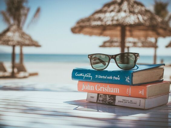 Une paire de lunettes posée sur des livres devant des paillotes