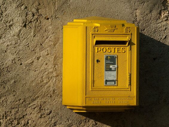 Une Boîte aux lettres jaune de la poste qui est accroché au mur