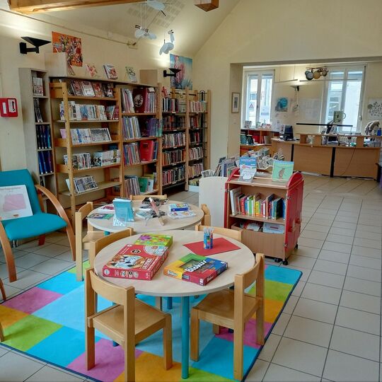 La salle de la bibliothèque avec des tables et des étagères sur lesquelles sont posés des livres et revues
